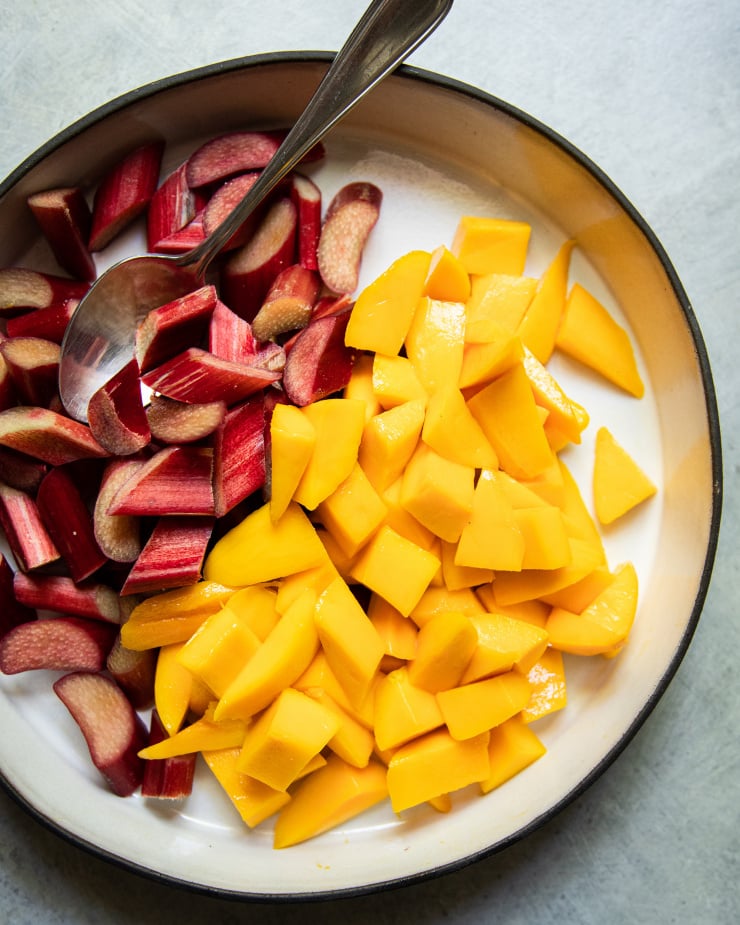 An up close, overhead shot of chopped rhubarb and mango pieces in a ceramic dish.