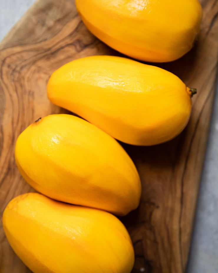 An up close, overhead shot of peeled Ataulfo mangos on a wood background.