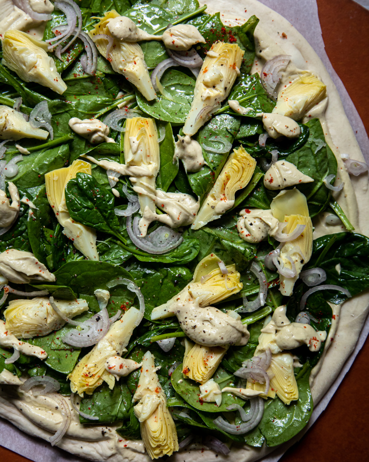 Overhead: up close image of an assembled, uncooked pizza.