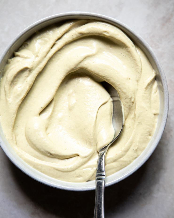 An up close overhead shot of a thick creamy white sauce in a bowl.