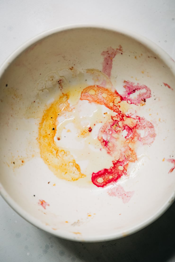 An overhead shot of pink and yellow beet stains in the bottom of a white bowl.