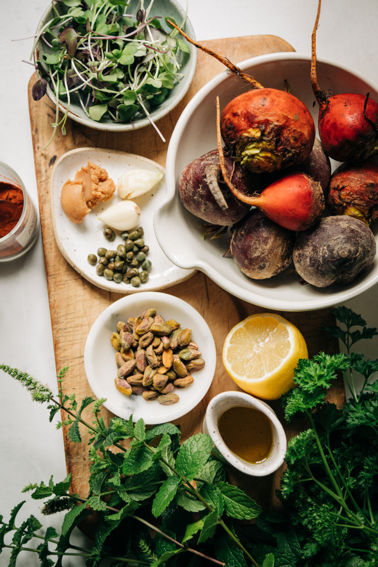 An overhead shot of ingredients for a grilled beet side dish with mint and parsley pistachio pesto.
