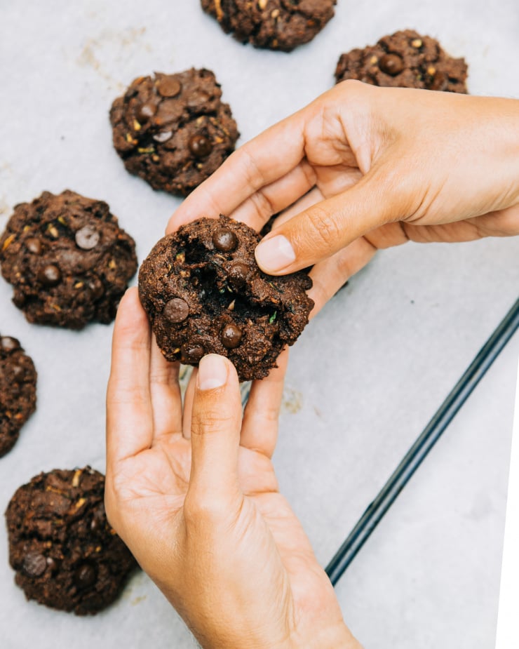 Overhead image shows a pair of hands breaking open a dark chocolate cookie-like treat.