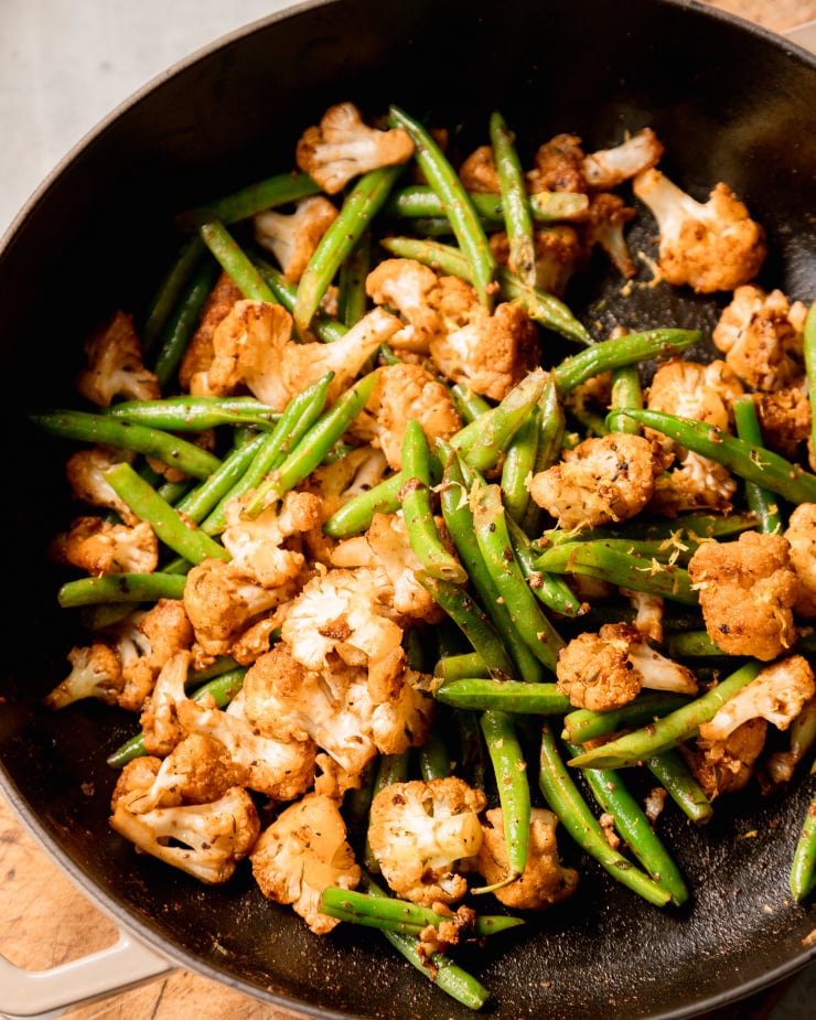 A 3/4 angle shot of sautéed green beans and cauliflower.