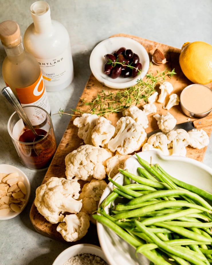 A 3/4 angle shot of ingredients for a cauliflower and green bean side dish.