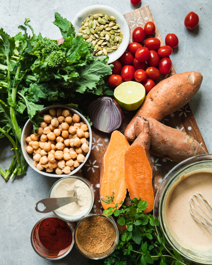 An overhead shot of ingredients for a healthy sheet pan dinner with sweet potatoes and broccoli rabe.