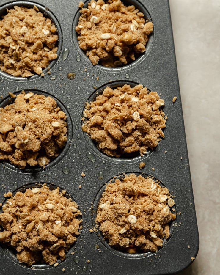 Image shows muffins topped with a crumble topping pre-baking.