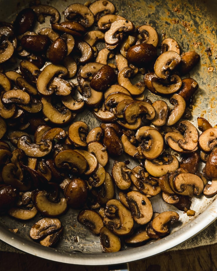 An overhead shot of sautéed sliced cremini mushrooms in a pan.