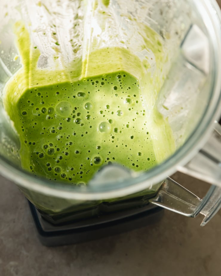 An overhead shot of pale green sauce in a blender pitcher.