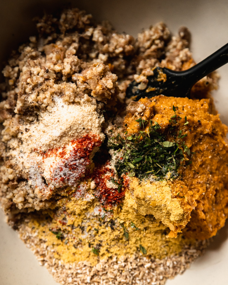 An up close, overhead shot of all of the ingredients used in a vegan squash patty recipe, in a mixing bowl.