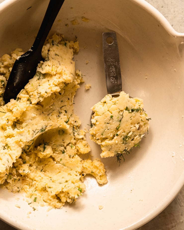 An overhead shot of a portion of waffle mixture that is flecked with chopped dill and green onions.