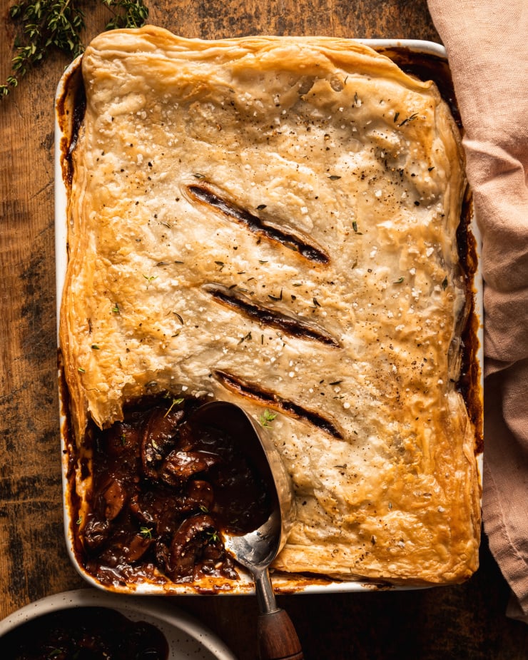 An overhead shot of a vegan mushroom bourguignon pot pie topped with golden puff pastry.