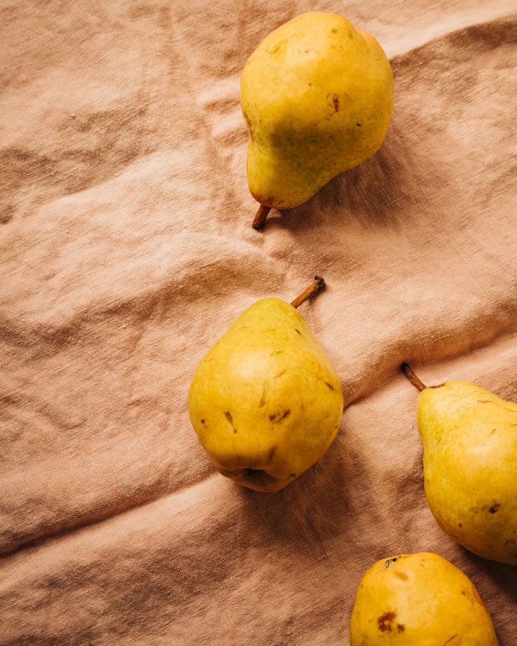 An overhead shot of ripe Bartlett pears on a pink linen napkin.