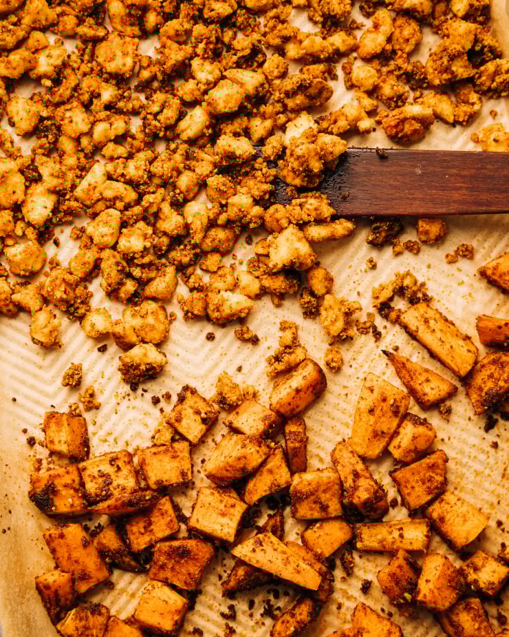 An overhead shot of crispy roasted tofu bits and cubes of sweet potato.