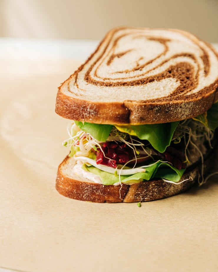 A 3/4 angle shot of an assembled veggie crunch sandwich on marble rye.