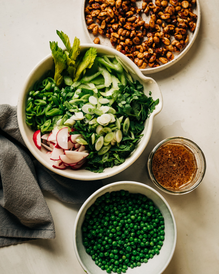 An overhead shot of prepped and chopped vegetables and herbs plus a jar of dressing for a noodle salad.