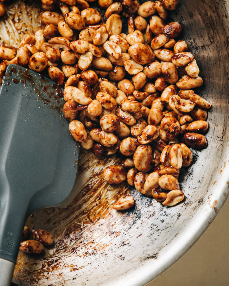 An up close shot of chili maple peanuts being glazed in a sauté pan.