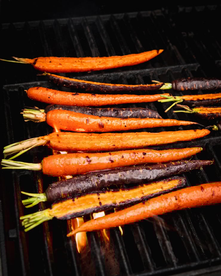 3/4 angle image shows carrots grilling on a barbecue.