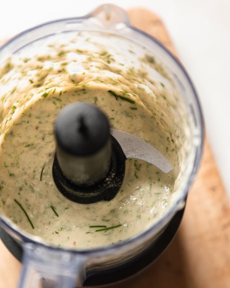 An overhead shot of vegan roasted garlic chive yogurt sauce mixed up in a small food processor.