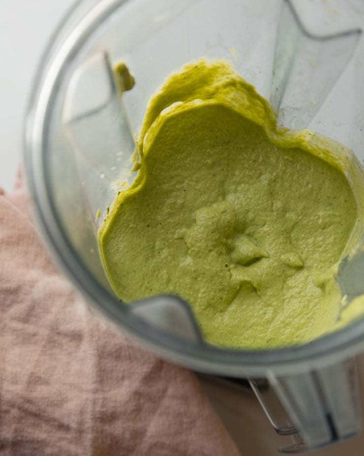 An overhead shot of a creamy green sauce in a blender pitcher.