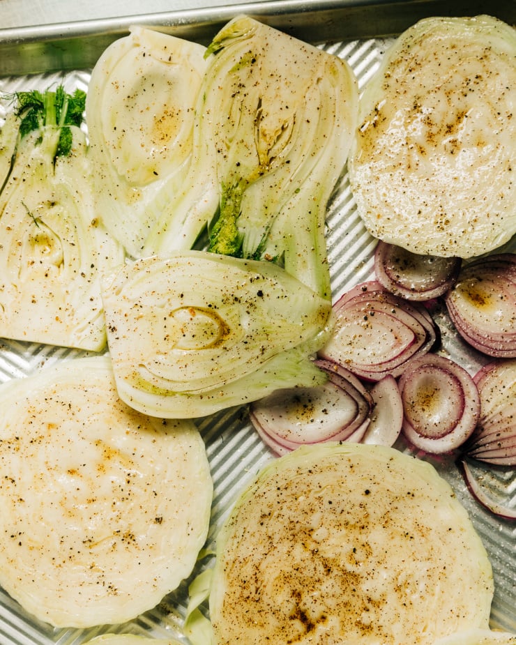 An overhead shot shows slices of cabbage, fennel and red onion brushed with a sumac infused olive oil.