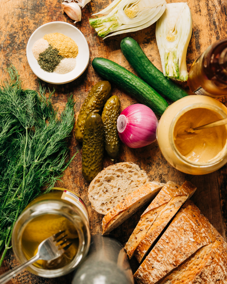 An overhead shot of ingredients for a pickle panzanella salad on top of a worn wooden board.