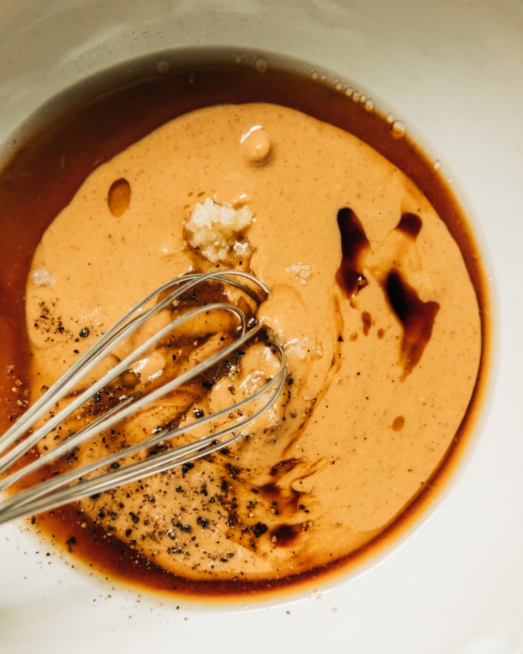 An up close, overhead shot of peanut sauce ingredients in a white bowl before being whisked together.