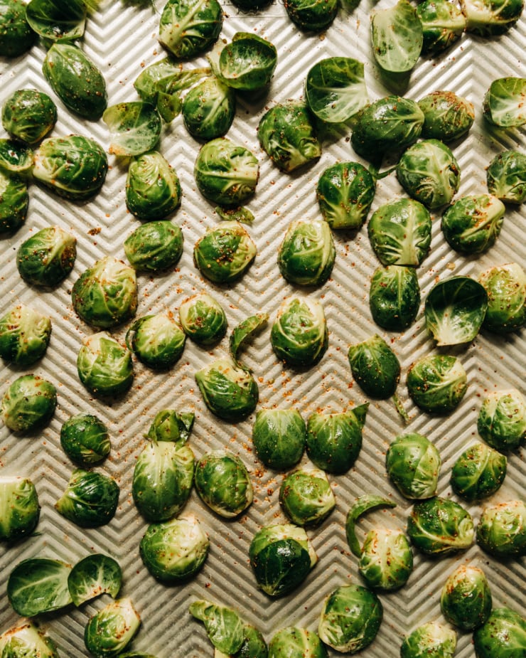 An overhead shot of brussels sprout halves tossed in oil and spices, set cut side down on a baking sheet.