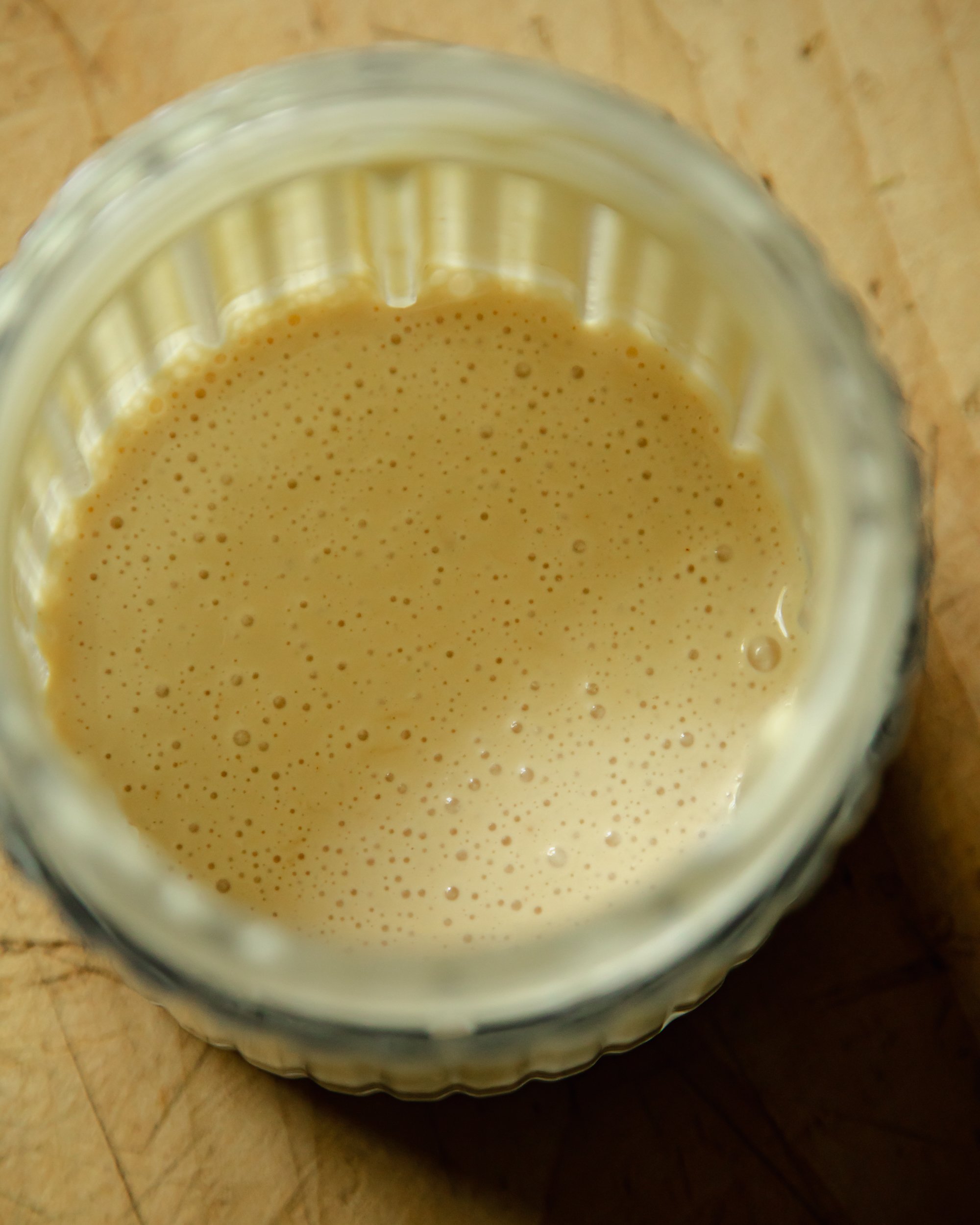 An overhead shot of a creamy white sauce in a small blender container.