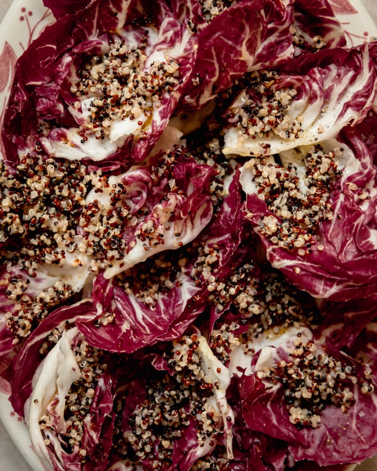 An up close, overhead shot shows leaves of radicchio holding cooked, multicolour quinoa grains.