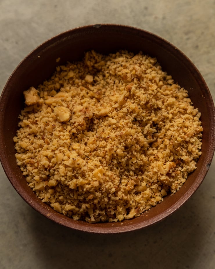 An overhead shot shows finely chopped walnuts in a small burgundy bowl.
