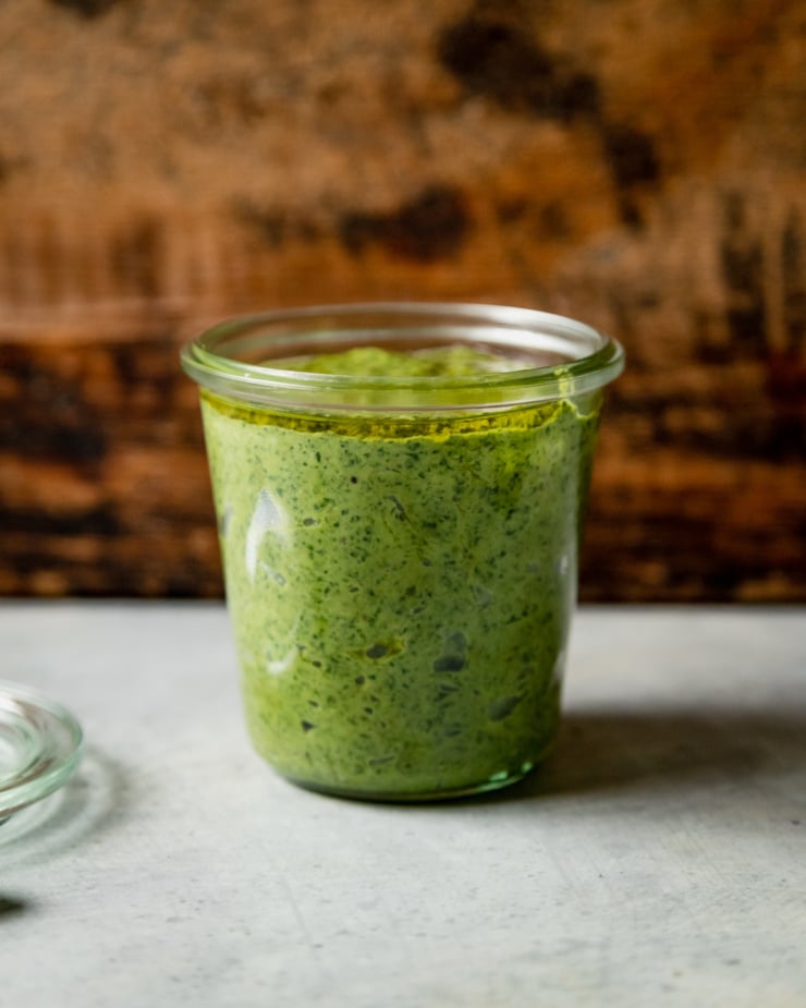 A head-on shot of a glass jar filled with vegan pesto.