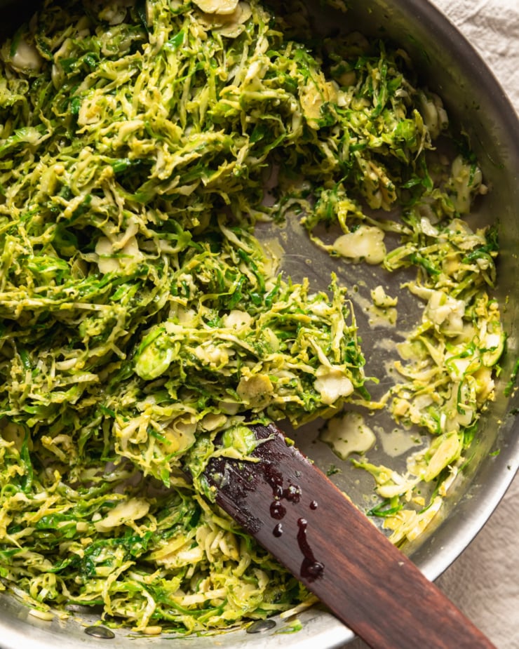 An overhead shot shows shredded brussels sprouts being sautéed in a pan.
