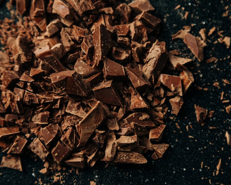 An overhead shot of chopped chocolate on a cutting board.
