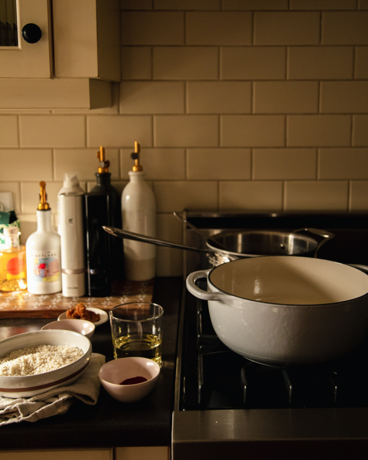 A head on shot of some pots on a gas stove with ingredient prep on the counter beside. The lighting is low and moody.
