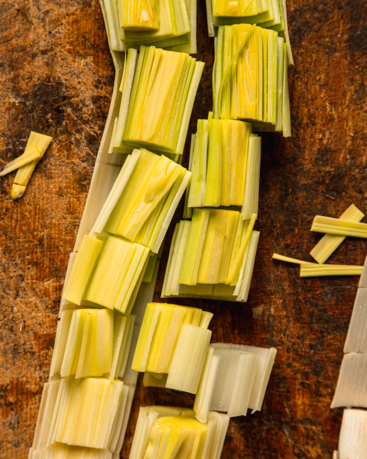 An overhead shot shows a leek that has been cut in half and then roughly chopped.