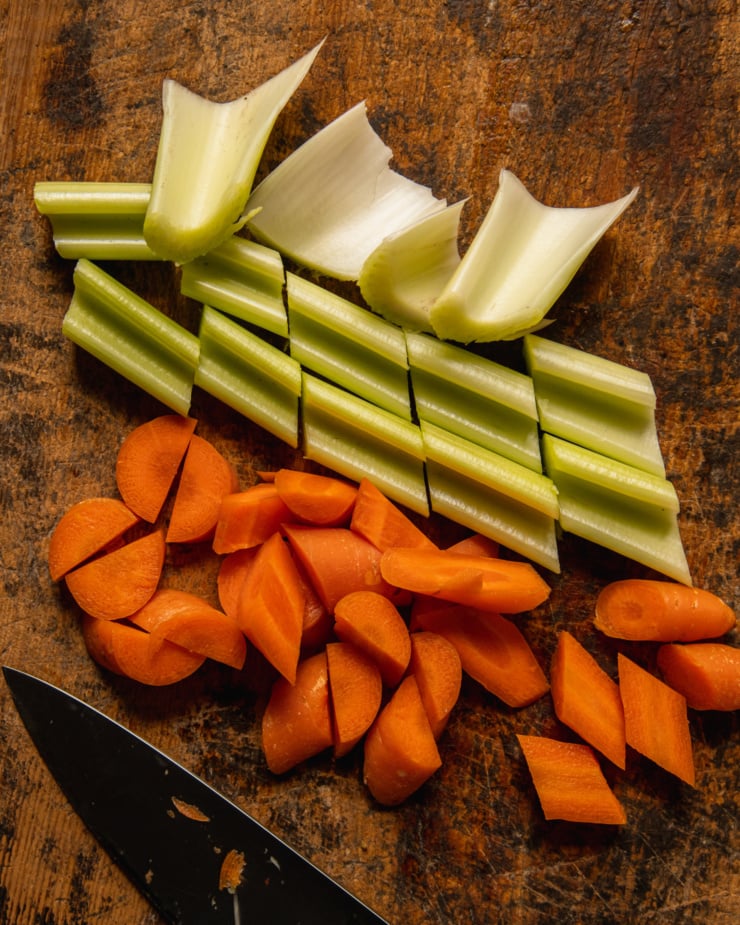 An overhead shot shows celery and carrots that have been roughly chopped.