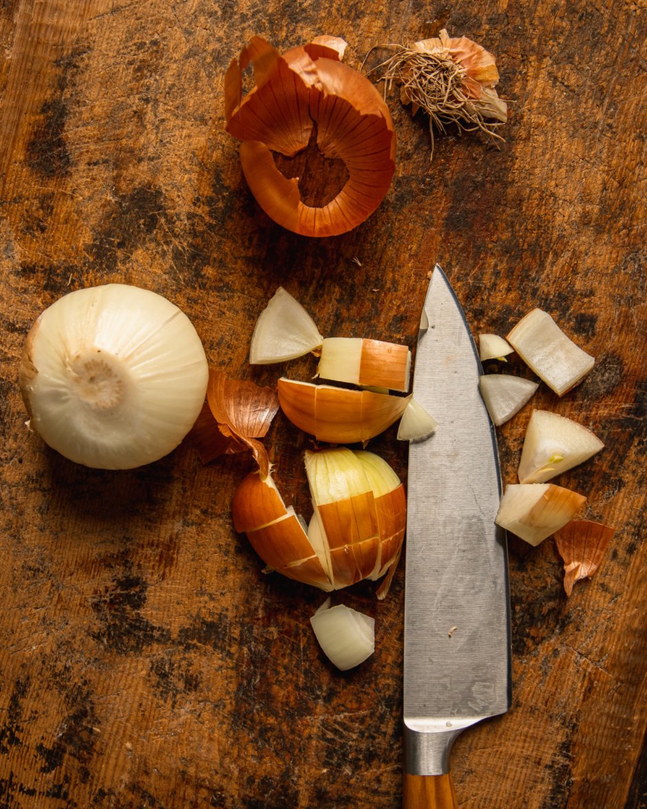 An overhead shot shows onion being roughly diced with some of their skin still intact.