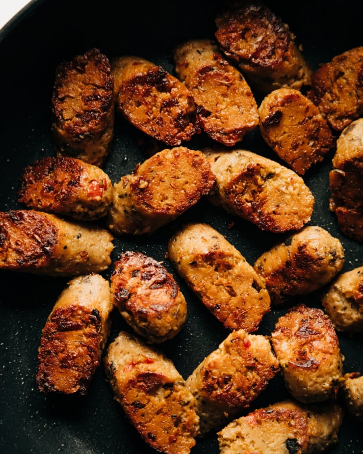 An up close, overhead shot of browned, sliced veggie sausage in a skillet.