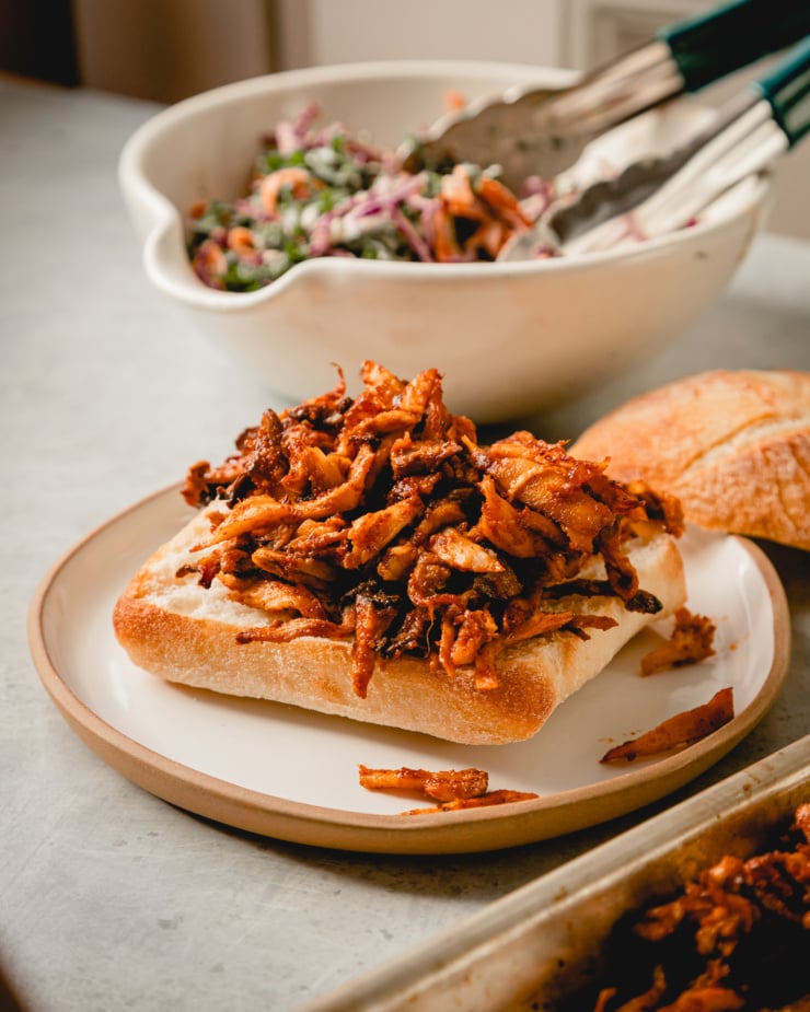 A 3/4 angle image shows shredded, BBQ sauce coated mushrooms on top of the bottom part of a ciabatta bun.