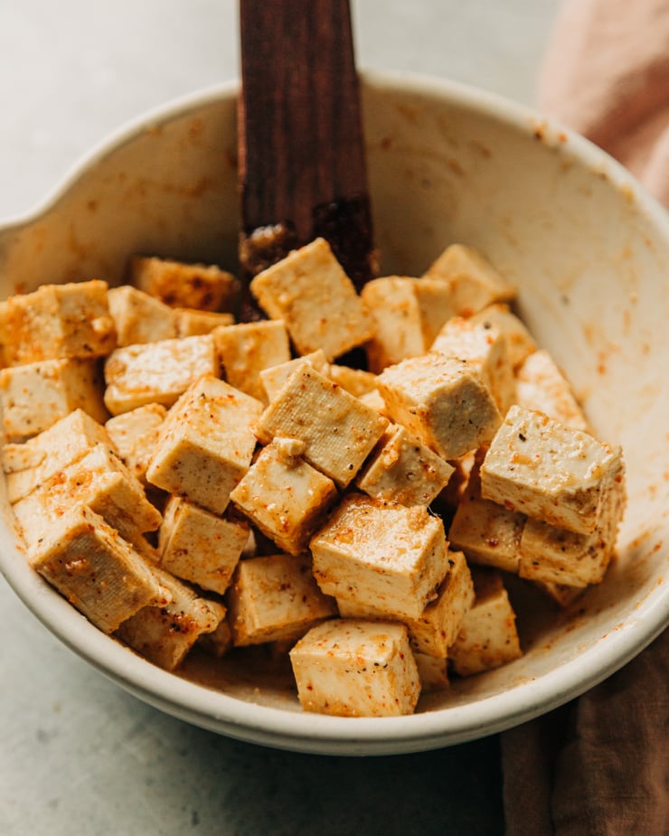 A 3/4 angle image shows cubes of tofu that have been tossed with oil, spices, Tamari, and arrowroot starch.