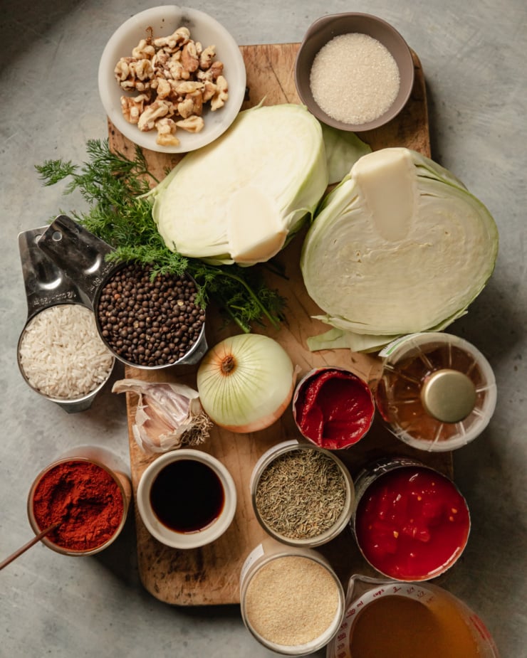 An overhead shot of ingredients used in a chopped vegan casserole skillet recipe. All ingredients are on top of a worn wooden cutting board or to the side of it.