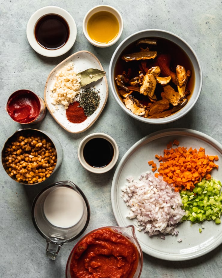An overhead shot shows prepped and chopped ingredients for a vegan lentil bolognese sauce.