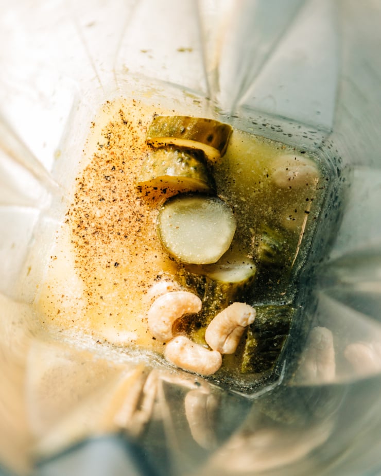 An overhead shot of ingredients for a creamy dill pickle salad dressing in the pitcher of a blender.