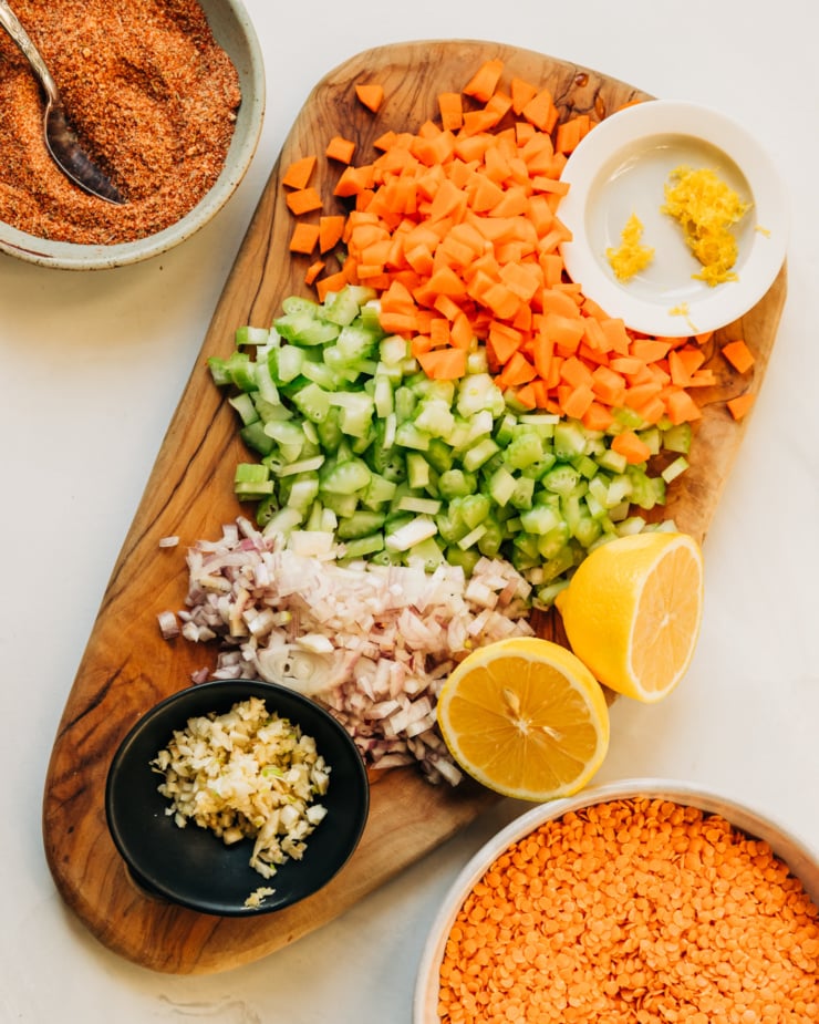 An overhead shot shows prepped vegetables, spices, and split red lentils.