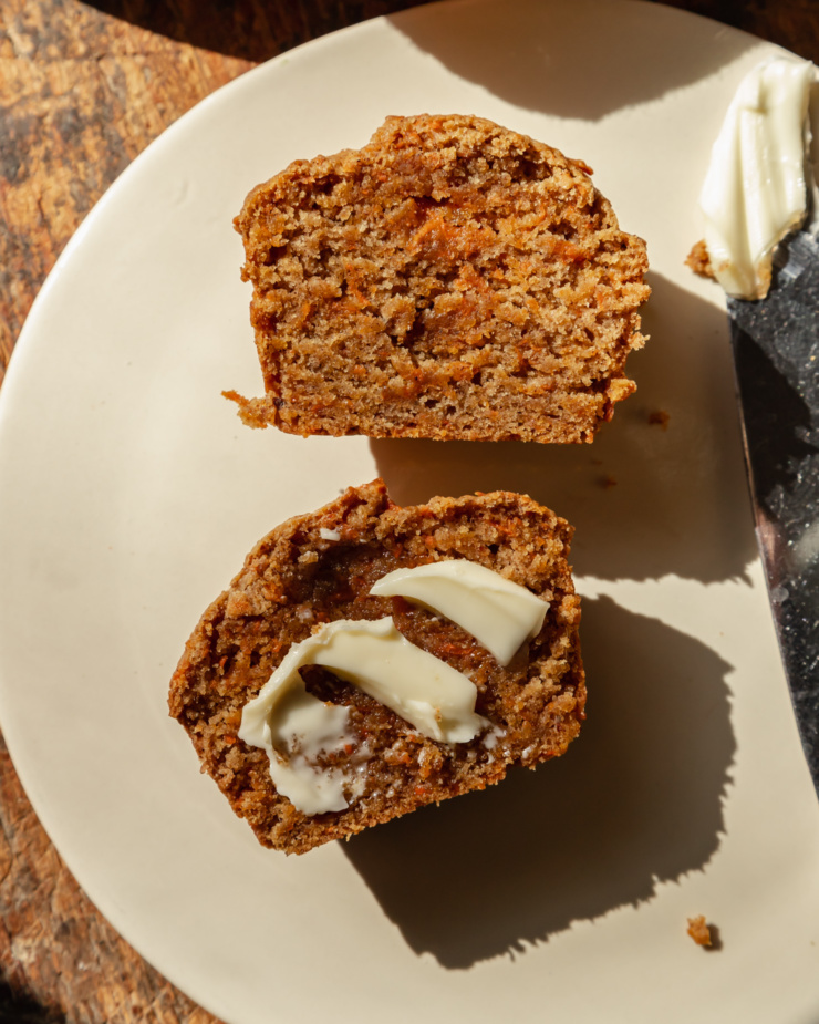 An up close, overhead shot of a split vegan carrot muffin with a swoop of vegan butter on one side.