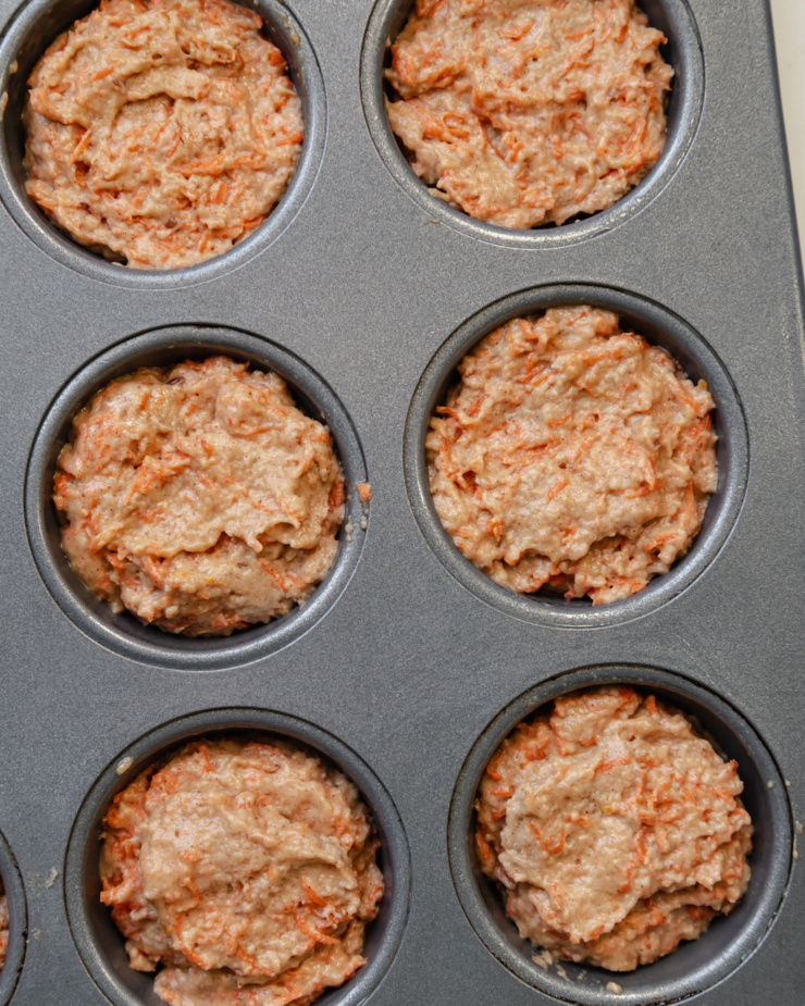 An overhead shot shows muffin batter portioned into a muffin tin.