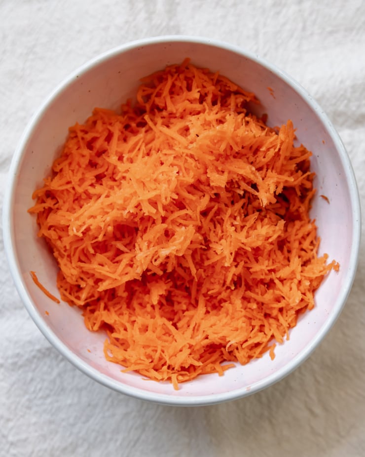 An up close, overhead shot of finely grated carrots in a bowl.