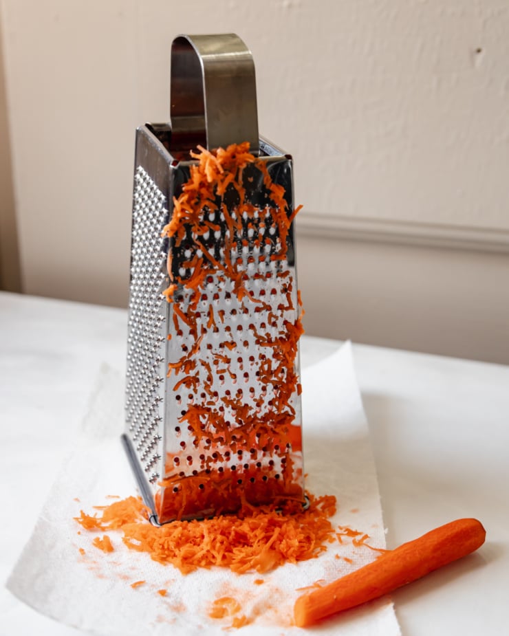 A head-on shot of a box grater that has been used to shred carrots.