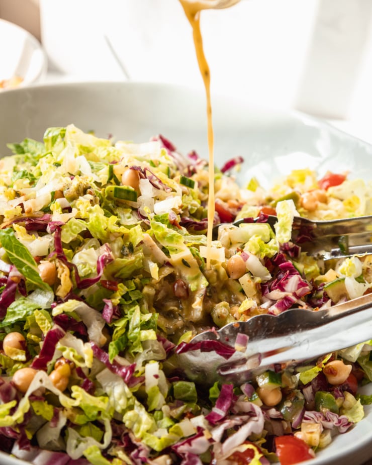 A head on shot of dressing being poured onto a salad.